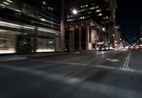 a view from the front seat of a car on a city street at night with lights shining and buildings in the background
