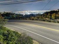 the view from a hill at night, looking down on a roadway and the city below