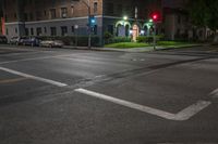 a red street light is green above the road intersection in front of a dark building