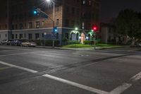 a red street light is green above the road intersection in front of a dark building