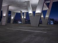 the view is at night in an empty area of concrete with lights and buildings below