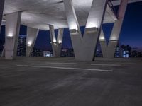 the view is at night in an empty area of concrete with lights and buildings below