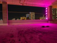 purple lights in an empty building with a view of the city below it at night