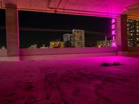 purple lights in an empty building with a view of the city below it at night