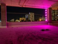 purple lights in an empty building with a view of the city below it at night