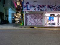 a night view of a street scene with the buildings lit up and graffiti on the building wall