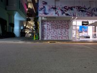 a night view of a street scene with the buildings lit up and graffiti on the building wall