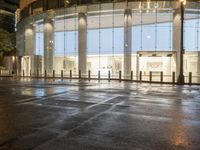 the empty space is very wet with a black and white checkered sidewalk outside a building