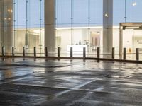 the empty space is very wet with a black and white checkered sidewalk outside a building