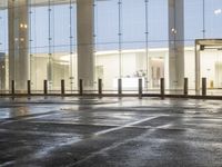 the empty space is very wet with a black and white checkered sidewalk outside a building
