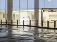 the empty space is very wet with a black and white checkered sidewalk outside a building