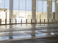 the empty space is very wet with a black and white checkered sidewalk outside a building
