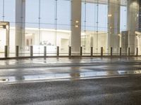 the empty space is very wet with a black and white checkered sidewalk outside a building