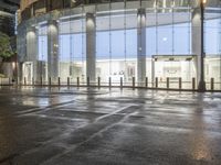 the empty space is very wet with a black and white checkered sidewalk outside a building