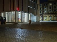 the car is parked in front of an empty building at night, next to a street