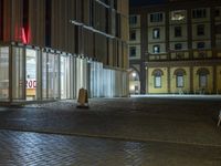 the car is parked in front of an empty building at night, next to a street