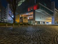 an empty cobblestone path in front of a lit building at night / photo by kevin stooke for flickrx