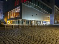 an empty cobblestone path in front of a lit building at night / photo by kevin stooke for flickrx