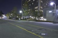 a empty street near an apartment complex at night with parking meters in the foreground