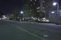 a empty street near an apartment complex at night with parking meters in the foreground