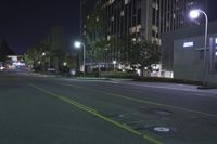 a empty street near an apartment complex at night with parking meters in the foreground