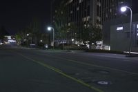 a empty street near an apartment complex at night with parking meters in the foreground