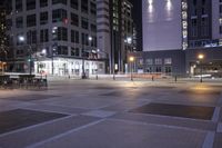 a very big empty area at night, with buildings in the background and traffic light on