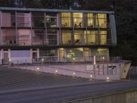 an empty parking lot with stairs in front of it at dusk with street lights on