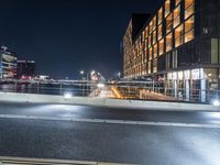 an empty city street that is illuminated by street lights at night near the water in the background