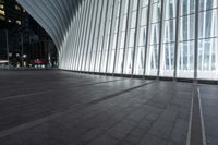 an empty concrete ground and some windows at night in a building with large vertical light panels and black flooring