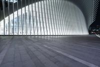 an empty concrete ground and some windows at night in a building with large vertical light panels and black flooring