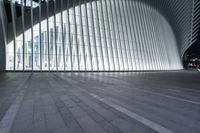 an empty concrete ground and some windows at night in a building with large vertical light panels and black flooring