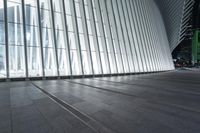 an empty concrete ground and some windows at night in a building with large vertical light panels and black flooring