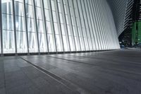 an empty concrete ground and some windows at night in a building with large vertical light panels and black flooring