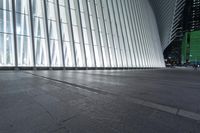 an empty concrete ground and some windows at night in a building with large vertical light panels and black flooring