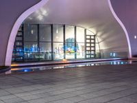 an empty empty sidewalk in front of a large building with lots of glass windows and doors