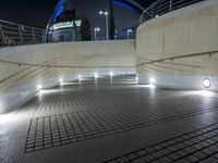 a paved walkway with lights and steps going up it's sides at night at a stadium