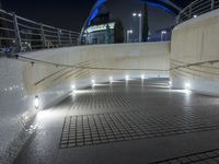 a paved walkway with lights and steps going up it's sides at night at a stadium