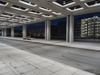 a bench sitting under an overhang at night in a city park area surrounded by concrete columns