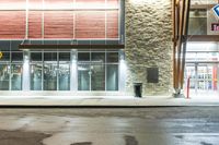 wet asphalt is on the side of an empty street at night with a building in the background