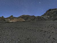 the view of the mountains at night from outside of a desert area, with stars shining brightly