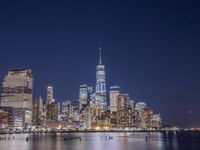 a view of a city at night with skyscrapers from the water's edge