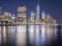 a view of a city at night with skyscrapers from the water's edge