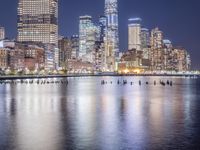a view of a city at night with skyscrapers from the water's edge