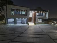 a modern home lit up with led lights, and the driveway is well paved for access