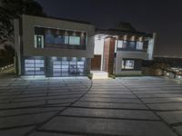 a modern home lit up with led lights, and the driveway is well paved for access