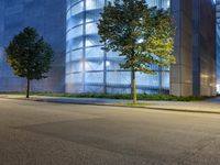 the exterior of an office building with several trees on both sides of it at night