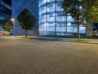 the exterior of an office building with several trees on both sides of it at night