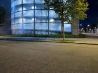 the exterior of an office building with several trees on both sides of it at night