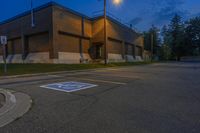 an empty parking lot sits in front of an office building at night in a suburban setting